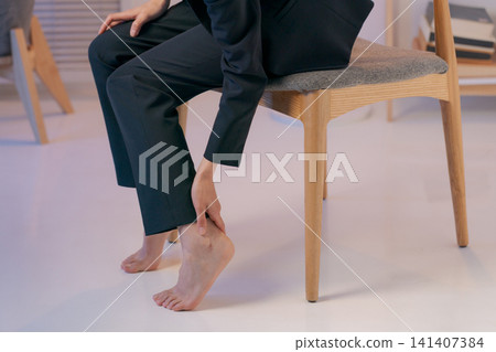 特寫鏡頭:一位身穿西裝的女子摀著腿。 特寫鏡頭:一位身穿西裝的女子摀著腿。 141407384