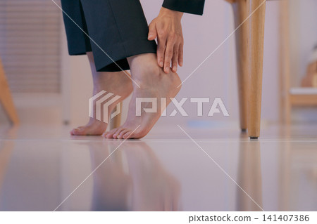 特寫鏡頭:一位身穿西裝的女子摀著腿。 特寫鏡頭:一位身穿西裝的女子摀著腿。 141407386