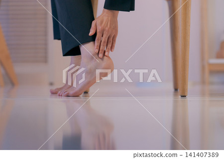 Close-up shot of a woman in a suit holding her leg. 141407389
