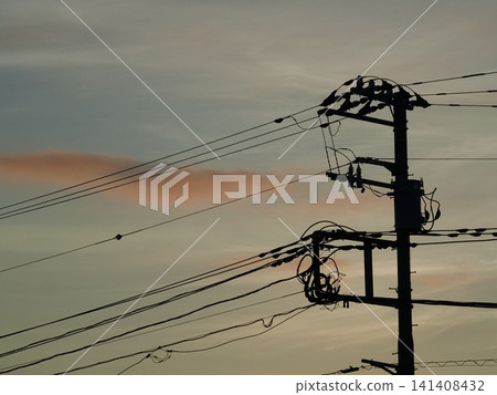 A telephone pole and the sky painted in the colors of the sunset. A telephone pole and the sky painted in the colors of the sunset. 141408432