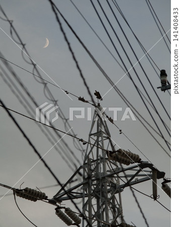A crescent moon at dusk and a high-voltage power line tower. A crescent moon at dusk and a high-voltage power line tower. 141408433