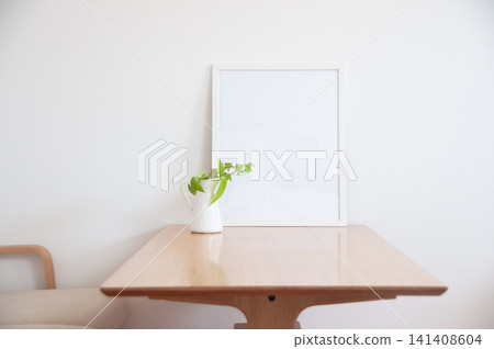 A small green plant placed on a simple wooden dining table. 141408604