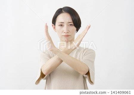 一名女子在白色背景前用雙臂擺出一個大大的「X」形。 141409061