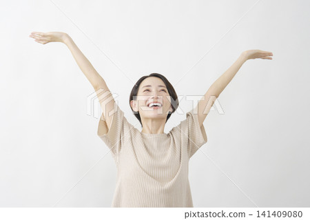 A woman stretches with her arms outstretched against a white background. A woman stretches with her arms outstretched against a white background. 141409080