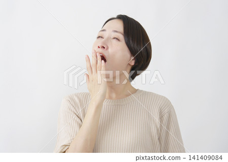 一位打哈欠的中年婦女，白色背景 141409084