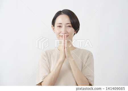 一位女子雙手合十，在白色背景前許願。 141409085