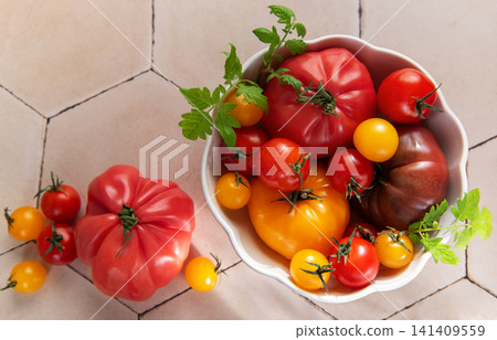 Fresh heirloom tomatoes in bowl on tile surface 141409559