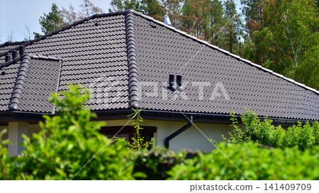 A single-family house with solar panels on a sunny day amidst green surroundings. Solar panels on roof of residential home providing ecofriendly green energy generation. A single-family house with solar panels on a sunny day amidst green surroundings. Solar panels on roof of residential home providing ecofriendly green energy generation. 141409709