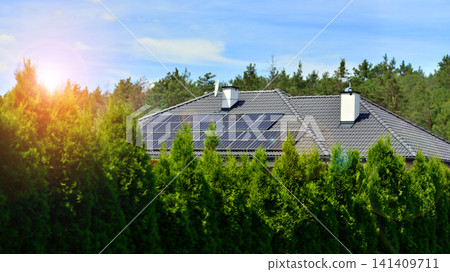 A single-family house with solar panels on a sunny day amidst green surroundings. Solar panels on roof of residential home providing ecofriendly green energy generation. A single-family house with solar panels on a sunny day amidst green surroundings. Solar panels on roof of residential home providing ecofriendly green energy generation. 141409711