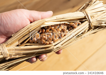A man holding natto (fermented soybeans) wrapped in rice straw. A man holding natto (fermented soybeans) wrapped in rice straw. 141410646