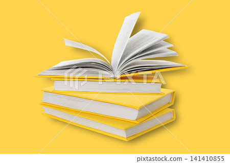 Books are shown on a yellow background with one book open Books are shown on a yellow background with one book open 141410855