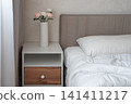 Modern bedroom interior with white bedding and bedside table 141411217