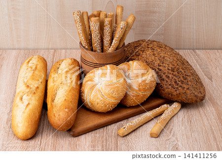 French baguettes. Fresh crispbread. Bread background. Different breed on wooden background. French baguettes. Fresh crispbread. Bread background. Different breed on wooden background. 141411256