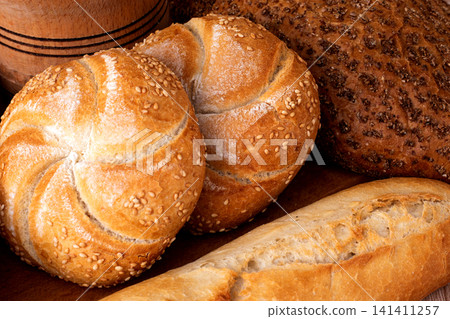 French baguettes. Fresh crispbread. Bread background. Different breed on wooden background. French baguettes. Fresh crispbread. Bread background. Different breed on wooden background. 141411257