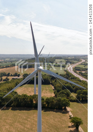 Tall Wind Turbine Standing in Green Farmland Under Sky Tall Wind Turbine Standing in Green Farmland Under Sky 141411308