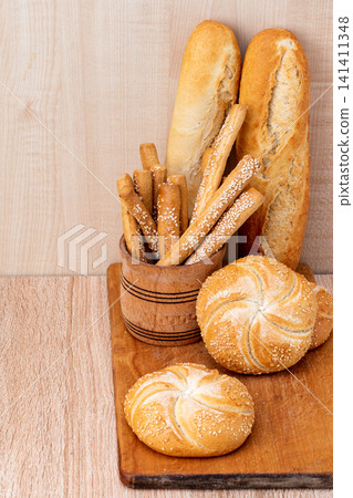French baguettes. Fresh crispbread. Bread background. Different breed on wooden background. French baguettes. Fresh crispbread. Bread background. Different breed on wooden background. 141411348