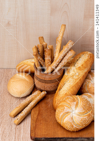 French baguettes. Fresh crispbread. Bread background. Different breed on wooden background. French baguettes. Fresh crispbread. Bread background. Different breed on wooden background. 141411349
