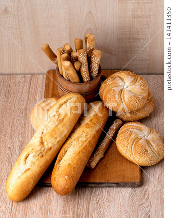 French baguettes. Fresh crispbread. Bread background. Different breed on wooden background. French baguettes. Fresh crispbread. Bread background. Different breed on wooden background. 141411350