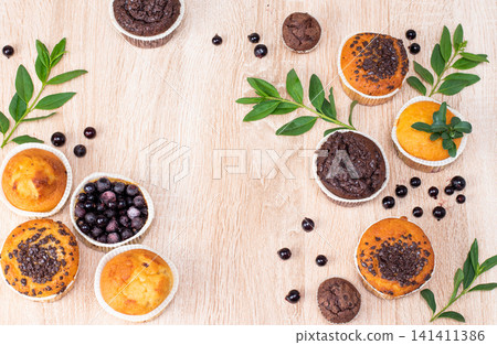 Chocolate muffin and nut muffin, homemade bakery on dark background. Muffin with blueberries on a wooden table. Fresh berries and sweet pastries on the board. Chocolate muffin and nut muffin, homemade bakery on dark background. Muffin with blueberries on a wooden table. Fresh berries and sweet pastries on the board. 141411386