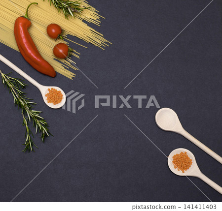 Italian food ingredients.Still life of cooking pasta on a black background top view. Wooden spoons with spices. Frame of products and vegetables. Italian food ingredients.Still life of cooking pasta on a black background top view. Wooden spoons with spices. Frame of products and vegetables. 141411403