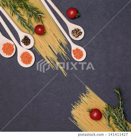 Italian food ingredients.Still life of cooking pasta on a black background top view. Wooden spoons with spices. Frame of products and vegetables. Italian food ingredients.Still life of cooking pasta on a black background top view. Wooden spoons with spices. Frame of products and vegetables. 141411427