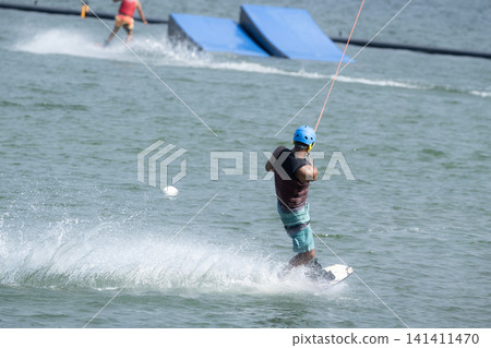 Cable Wakeboarder Riding on Lake in Summer. Cable Wakeboarder Riding on Lake in Summer. 141411470