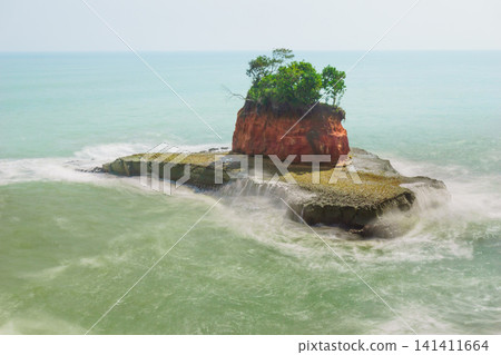 Aerial view of coastal rock formations rising from the sea with crashing waves and sandy beach in Indonesia Aerial view of coastal rock formations rising from the sea with crashing waves and sandy beach in Indonesia 141411664