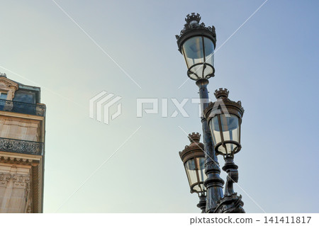 Ornate Parisian street lamp contrasting with a classic Haussmann building under a clear blue sky, travel destination Ornate Parisian street lamp contrasting with a classic Haussmann building under a clear blue sky, travel destination 141411817