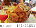 Traditional baguette pieces in wicker basket on restaurant table in Paris, enjoying French cuisine 141411831
