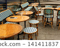 Empty outdoor tables and chairs at a traditional Parisian cafe terrace, ready for customers on a classic cobbled street 141411837