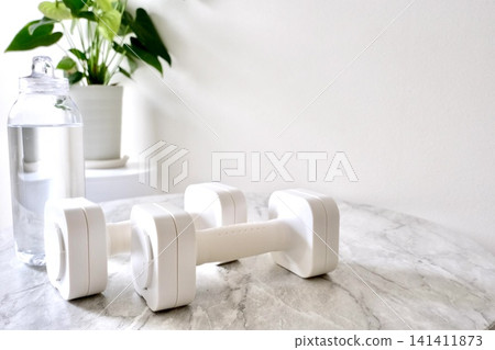 An indoor scene depicting hydration and strength training. 141411873