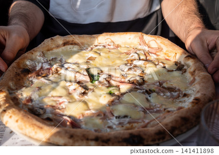 Naples, italy. December 30, 2024. Freshly baked neapolitan pizza with melted mozzarella, prosciutto, and mushrooms, ready to eat in naples, italy 141411898