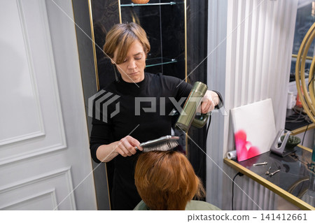 Young female hairdresser styling a haircut with a styler. in beauty salon Stock Photo 141412661