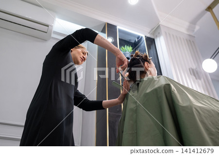 Young female hairdresser stylist working with scissors in beauty salon Stock Photo 141412679