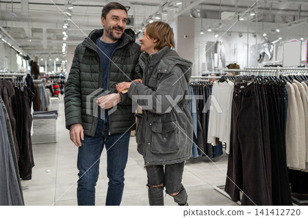 Positive man and woman having fun in the clothes store. Shopping together concept. Positive man and woman having fun in the clothes store. Shopping together concept. 141412720