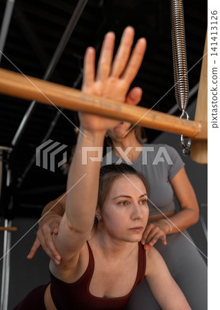 Woman doing Swan exercise on Pilates Reformer for the chest and back muscles, focusing on flexibility, strength, and control with determination. Woman doing Swan exercise on Pilates Reformer for the chest and back muscles, focusing on flexibility, strength, and control with determination. 141413126