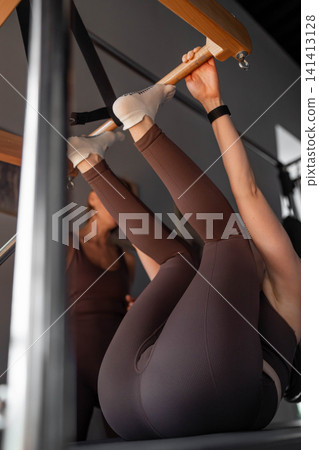 Woman doing pilates foot work and core exercise on Balanced Body Cadillac machine at studio, focusing on strength and fexibility Woman doing pilates foot work and core exercise on Balanced Body Cadillac machine at studio, focusing on strength and fexibility 141413128