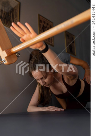 Woman doing Swan exercise on Pilates Reformer for the chest and back muscles, focusing on flexibility, strength, and control with determination. Woman doing Swan exercise on Pilates Reformer for the chest and back muscles, focusing on flexibility, strength, and control with determination. 141413448