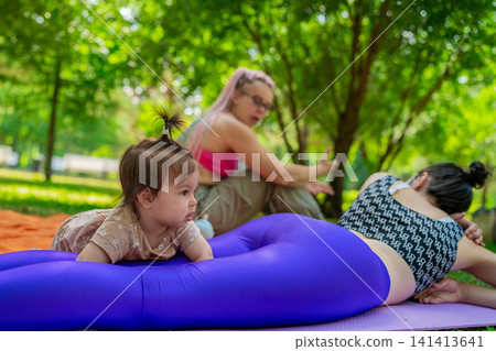 Mother and child resting and relaxing after yoga class on mat under trees in green park. Resting, yoga, mat, trees, mother, child. Mother and child resting and relaxing after yoga class on mat under trees in green park. Resting, yoga, mat, trees, mother, child. 141413641
