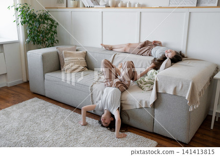 Friends standing upside down on hands and relaxing in cozy living room with plants and soft window light. Relaxing, sitting, friends, cozy, living room, plants. Friends standing upside down on hands and relaxing in cozy living room with plants and soft window light. Relaxing, sitting, friends, cozy, living room, plants. 141413815