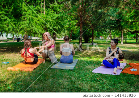 Mothers and daughters participating together in yoga class on mats enjoying outdoor fitness in park. Family yoga, mats, mothers, daughters, park. Mothers and daughters participating together in yoga class on mats enjoying outdoor fitness in park. Family yoga, mats, mothers, daughters, park. 141413920