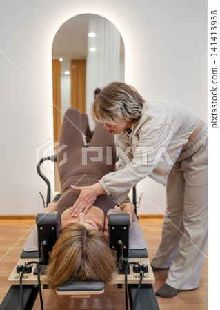 Woman training on the reformer bed at Glute bridge Pilates workout. Reformer pilates studio machine for fitness workouts in gym. Fit, healthy and strong authentical body. Fitness concept Woman training on the reformer bed at Glute bridge Pilates workout. Reformer pilates studio machine for fitness workouts in gym. Fit, healthy and strong authentical body. Fitness concept 141413938