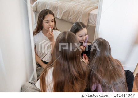 Girls laughing together talking at bed edge in cozy modern bedroom with large mirror. Laughing, bed, girls, mirror, cozy, modern, bedroom. Girls laughing together talking at bed edge in cozy modern bedroom with large mirror. Laughing, bed, girls, mirror, cozy, modern, bedroom. 141414047