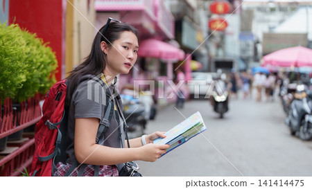 Asian woman tourist with backpack and map exploring city street during summer travel vacation Asian woman tourist with backpack and map exploring city street during summer travel vacation 141414475