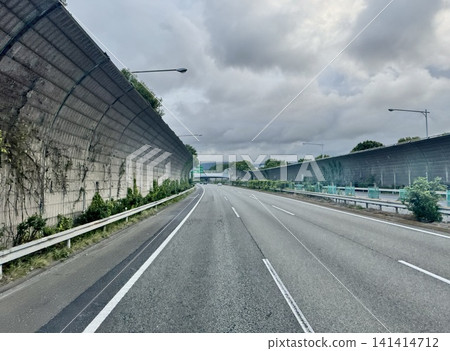 A cloudy day on a highway with sound barriers; a road scene running through the suburbs. A cloudy day on a highway with sound barriers; a road scene running through the suburbs. 141414712