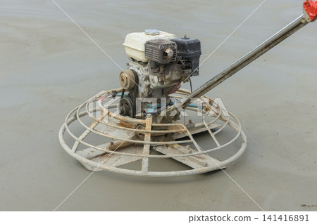 Trowel machine is working to finish surface of wet concrete on building site. Trowel machine is working to finish surface of wet concrete on building site. 141416891