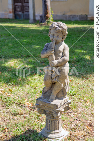 Stone cherub statue playing flute in Dajla monastery garden, Croatia. Stone cherub statue playing flute in Dajla monastery garden, Croatia. 141416920