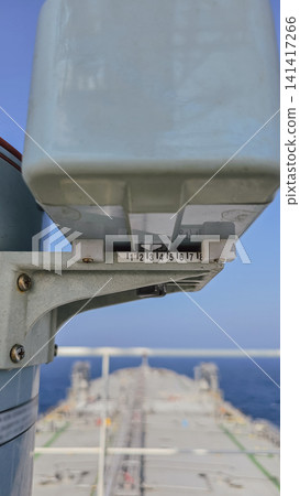 Close up view of navigational equipment repeater on bridge wing of oil tanker ship with vessel bow and open sea background during sunny navigation day Close up view of navigational equipment repeater on bridge wing of oil tanker ship with vessel bow and open sea background during sunny navigation day 141417266