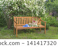 Blue hat, wicker basket with summer vegetable on a wooden bench in a blooming summer garden 141417320