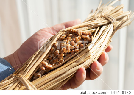 一名男子手捧著用稻草包裹的納豆(發酵大豆)。 一名男子手捧著用稻草包裹的納豆(發酵大豆)。 141418180